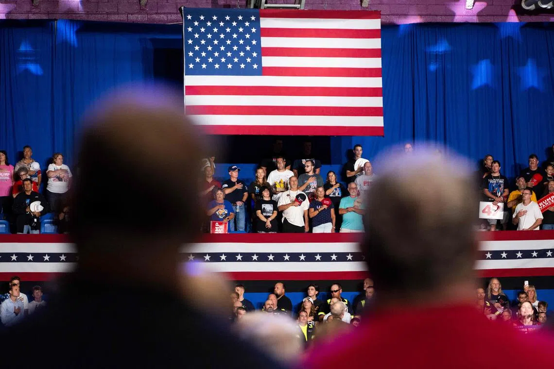 A crowd of supporters of former US President and presidential candidate Donald Trump say the allegiance to the US flag before Trump spoke during a campaign stop in the Cambria County War Memorial in Johnstown, Pennsylvania on August 30, 2024. For someone who avoided the military draft, grew up in pampered wealth and plays golf as his main outdoor activity, Donald Trump has been doing the implausible for years: attracting macho voters to his presidential campaigns. Now he must navigate a new wrinkle: how that manufactured machismo and an anti-feminist belligerence plays against Kamala Harris and her quest to become America's first woman president. (Photo by ROBERTO SCHMIDT / AFP)