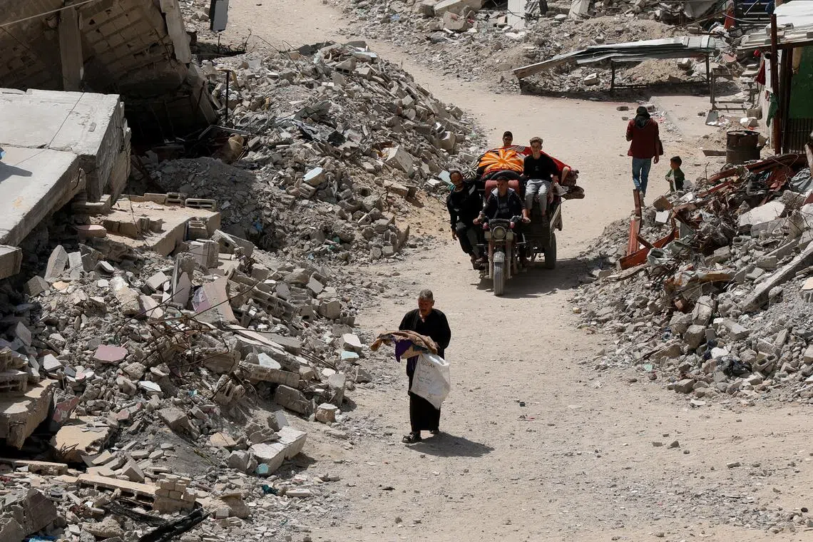 Palestinians move along a path near the rubble of houses, in Khan Younis in the southern Gaza Strip, April 3, 2025. REUTERS/Hatem Khaled
