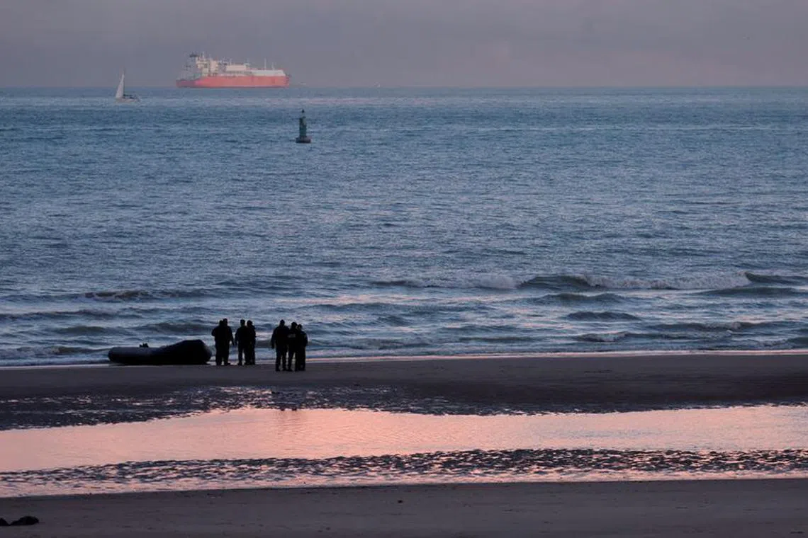 FILE PHOTO: French policemen stand beside a dinghy lying on the beach after migrants tried to start the engine of a rubber dinghy they wanted to use to leave the coast of northern France and to cross the English Channel, in Sangatte near Calais, France, November 29, 2022.  REUTERS/Pascal Rossignol