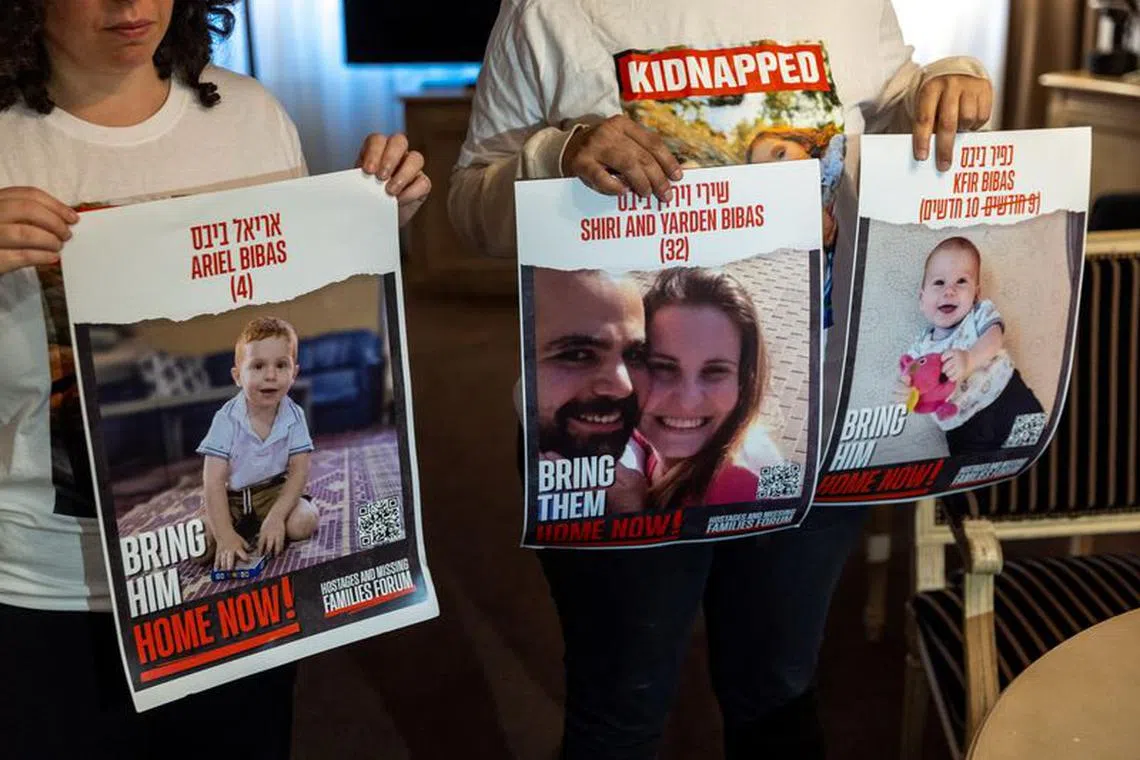 FILE PHOTO: Ofri Bibas Levy, whose brother Yarden (34) was taken hostage with his wife Shiri (32) and 2 children Kfir (10 months) and Ariel (4),  holds with her friend Tal Ulus pictures of them during an interview with Reuters, as the conflict between Israel and the Palestinian Islamist group Hamas continues, in Geneva, Switzerland, November 13, 2023. REUTERS/Denis Balibouse/File Photo
