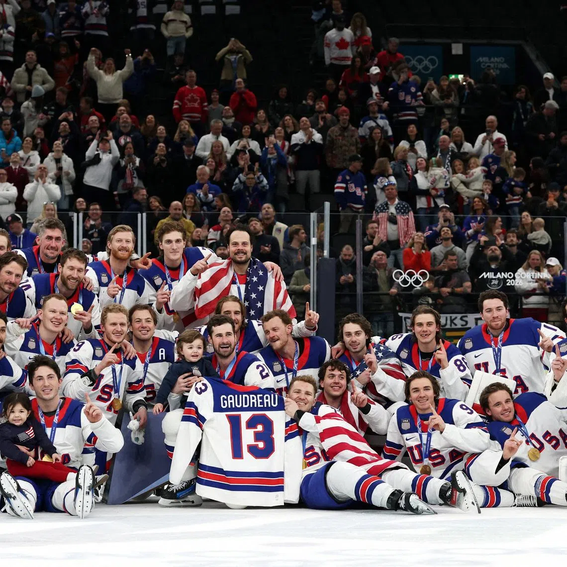 Milano Cortina 2026 Olympics - Ice Hockey - Men's Victory Ceremony - Milano Santagiulia Ice Hockey Arena, Milan, Italy - February 22, 2026. Gold medalists United States hold up the jersey of the late John Gaudreau and celebrate with his children, Noa Harper Gaudreau and Johnny Edward Gaudreau, as they pose for a photograph and celebrate with their medals during the ceremony REUTERS/Mike Segar