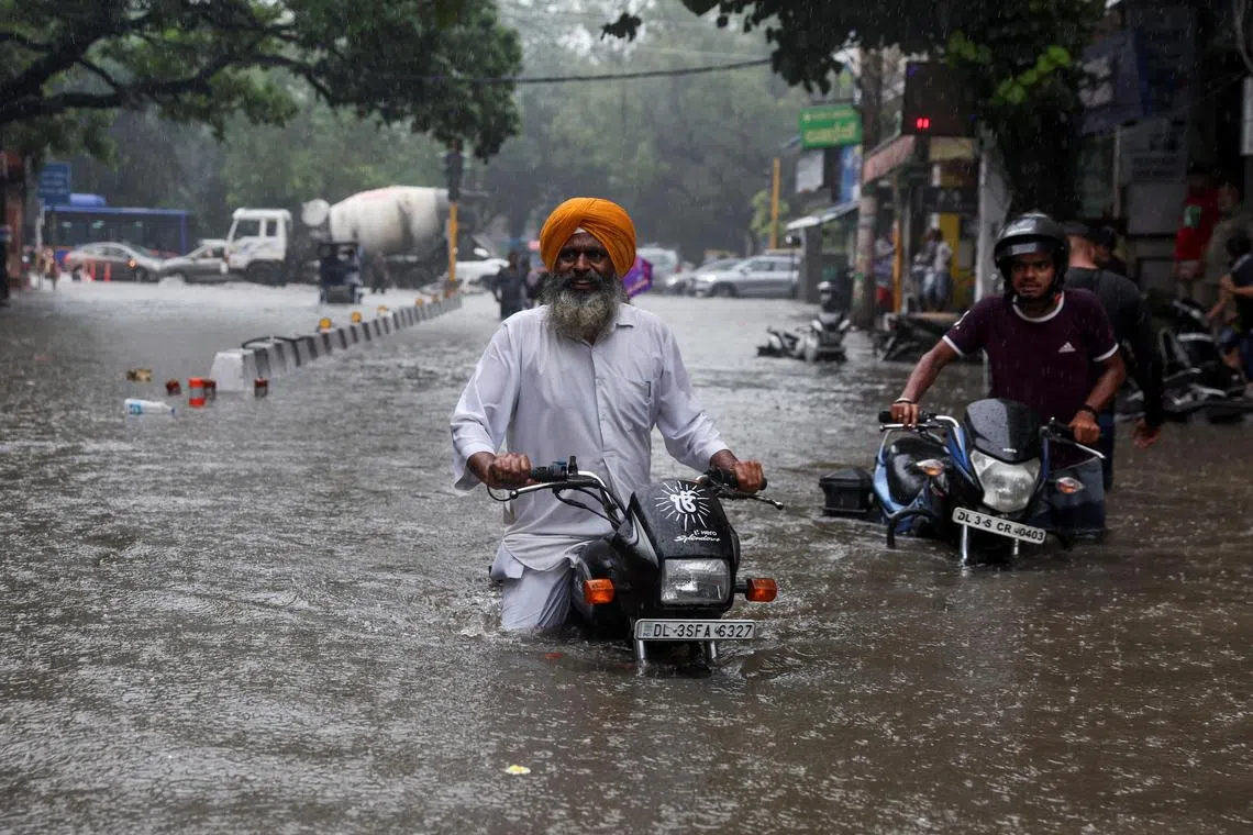 A man on his motorbike wades through a flooded street after heavy rains in New Delhi, India on July 8, 2023. 