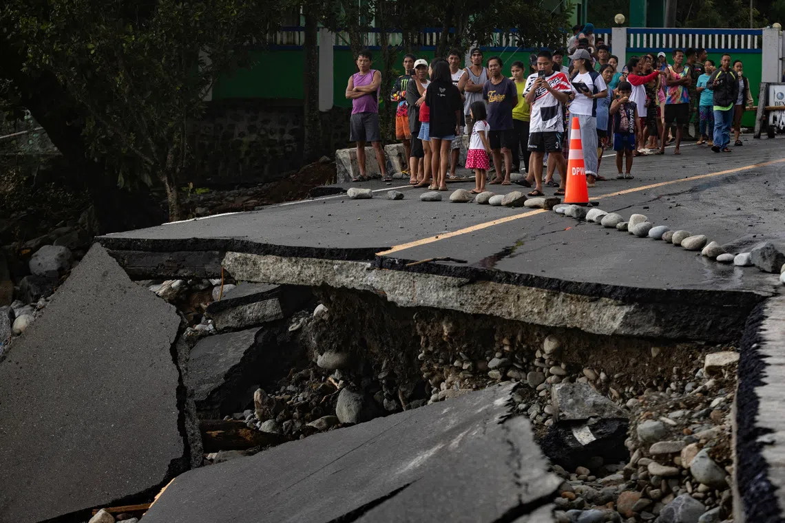 People standing near a wrecked part of the Baler-Casiguran road a day after Typhoon Fung-wong made landfall in Dipaculao, Aurora, Philippines on Nov 10, 2025. 