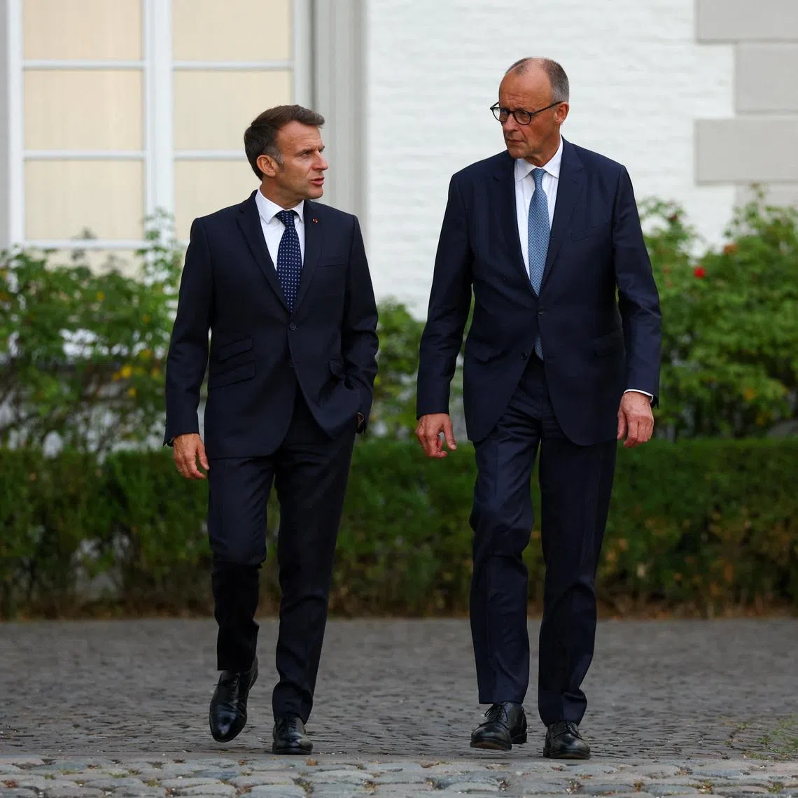 German Chancellor Friedrich Merz and French President Emmanuel Macron walk, on the day of their meeting at Grandhotel Schloss Bensberg, in Bensberg, Bergisch Gladbach, Germany, July 16, 2026. REUTERS/Thilo Schmuelgen