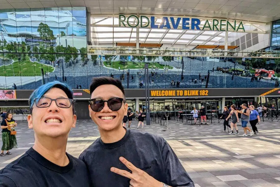 Two Asian Singaporean men standing outside Melbourne’s Rod Laver Arena to watch the  Blink-182 concert