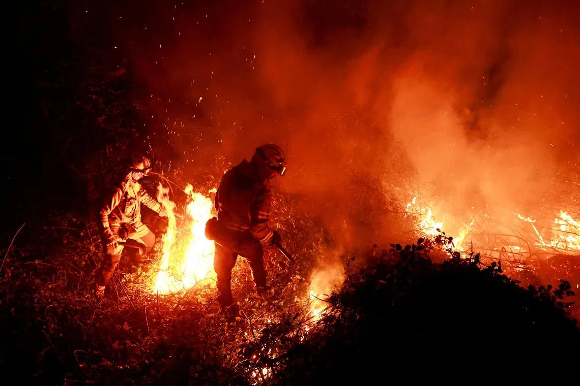 Galician firefighters tackle flames in a forest in Piedrafita, in the Asturias region of Spain.