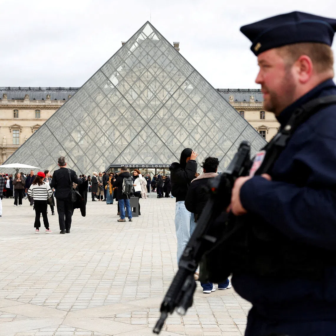 FILE PHOTO: A French CRS riot police officer patrols near the glass Pyramid of the Louvre Museum, after French police arrested suspects in the Louvre heist case, in Paris, France October 27, 2025. REUTERS/Abdul Saboor/File Photo