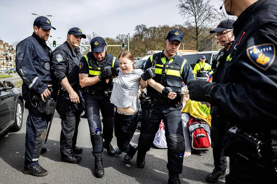 Swedish climate activist Greta Thunberg (centre) is arrested during a climate march against fossil subsidies near the highway A12 in the Hague, on April 6, 2024. 