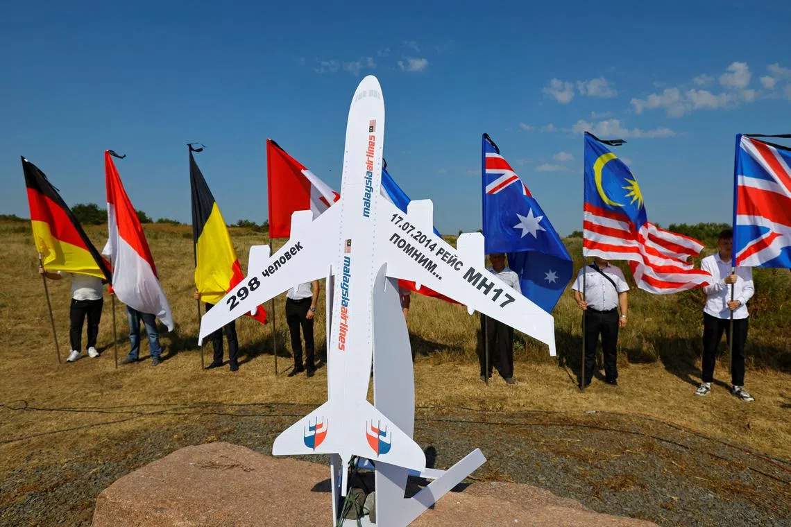 People hold flags at a memorial to victims of the Malaysia Airlines Flight MH17 plane crash during a ceremony marking the 10th anniversary of the accident, near the village of Hrabove (Grabovo) in the Donetsk region, Russian-controlled Ukraine, July 17, 2024. REUTERS/Alexander Ermochenko