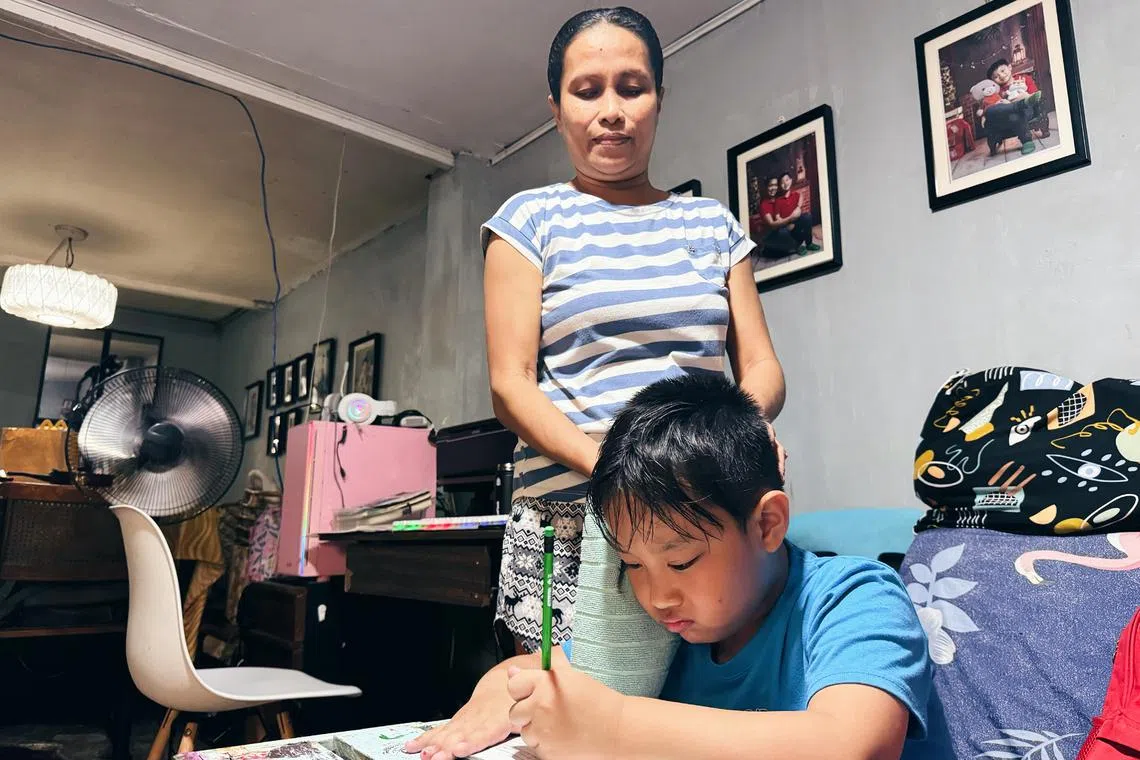 Filipino student Daryl Siongco doing his homework at home in Quezon City, while his nanny dries his sweat, amid the warm weather on April 2.