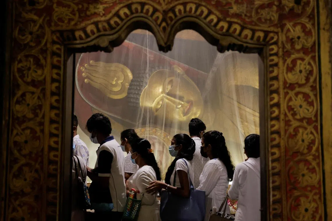Devotees walking past a statue of Buddha as they worship on Vesak day to commemorate the birth, enlightenment and death of Buddha, at Kelaniya Buddhist temple, in Colombo, Sri Lanka on May 5, 2023. 

