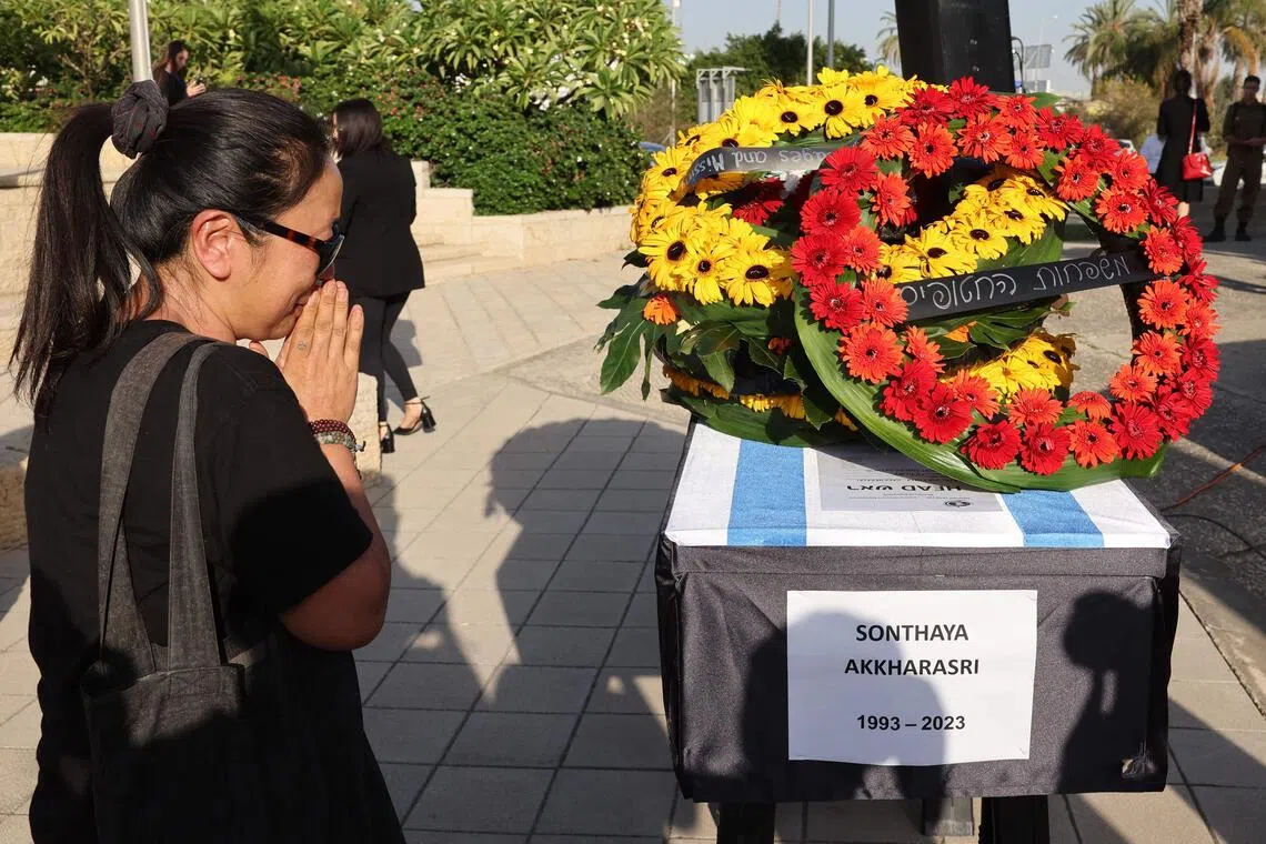 A relative of Thai national Sonthaya Oakkharasri, who killed in the Oct 7, 2023, attack by Palestinian militants, stands next to his coffin during a farewell ceremony at the Ben Gurion Airport in Tel Aviv.