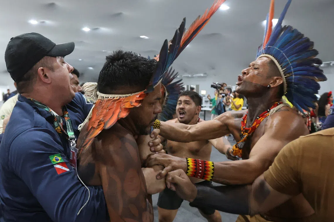 An Indigenous demonstrator is held by a staff member as protesters force their way into the venue hosting the UN Climate Change Conference (COP30), in Belem, Brazil, November 11, 2025. REUTERS/Anderson Coelho