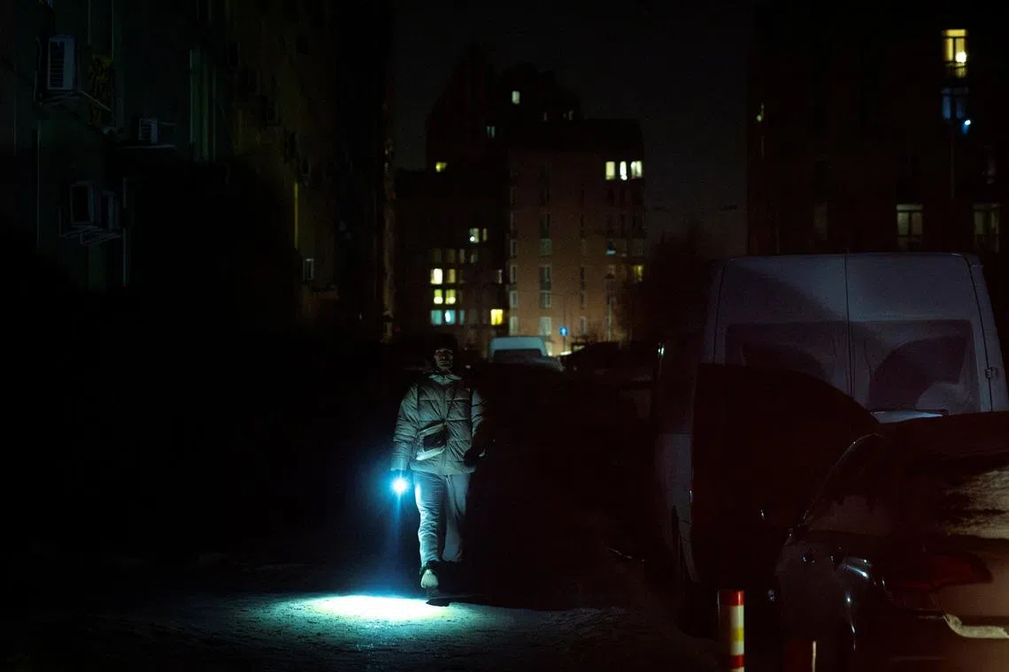 A man carries a torch as he walks a dark street in a neighborhood left without electricity after recent Russian strikes on the capital’s civilian infrastructure, amid Russia's attack on Ukraine, during sub-zero temperatures in Kyiv, Ukraine January 24, 2026.  REUTERS/Thomas Peter