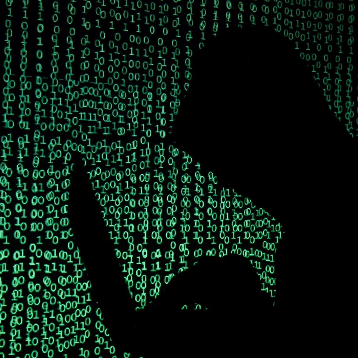 A hooded man holds a laptop computer as cyber code is projected on him in this illustration picture taken on May 13, 2017. REUTERS/Kacper Pempel/Illustration