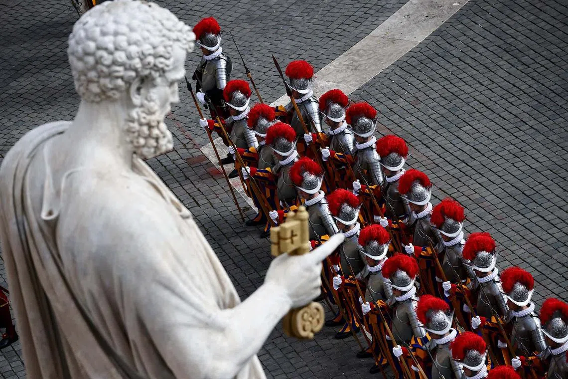 Members of the Swiss Guard standing near a statue in St. Peter's Square on the day of the Easter Sunday Mass at the Vatican, April 20, 2025. 