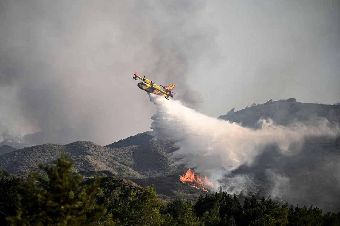 A fire fighting aircraft drops water over a wildfire close to village of Vati  in the southern part of the Greek island of Rhodes.