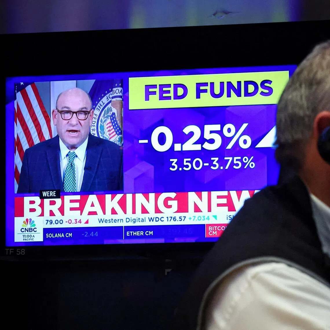 A screen displays the Fed rate announcement as a trader works on the floor of the New York Stock Exchange, in New York City, on Dec 10.