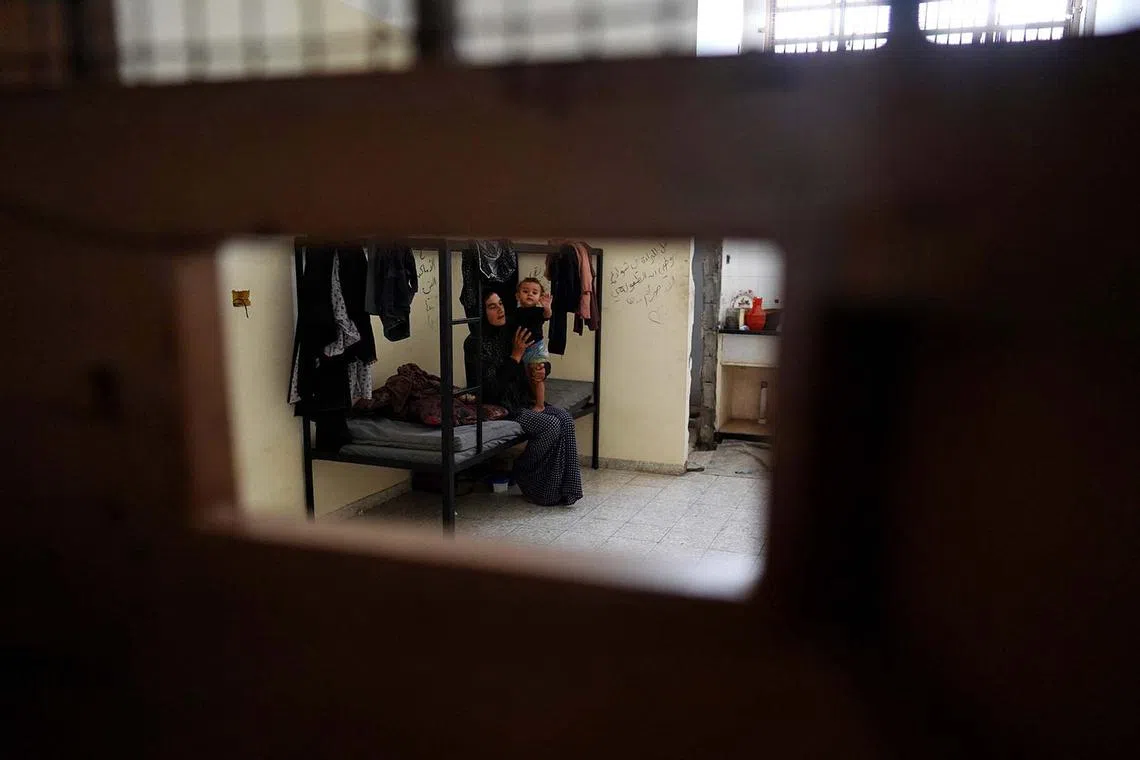 TOPSHOT - A Palestinian woman plays with her baby in one of the cells of the Asdaa Central Prison which has become a shelter for displaced people in Khan Yunis in the southern Gaza Strip on August 14, 2024, amid the ongoing conflict between Israel and the Hamas militant group. (Photo by Bashar TALEB / AFP)