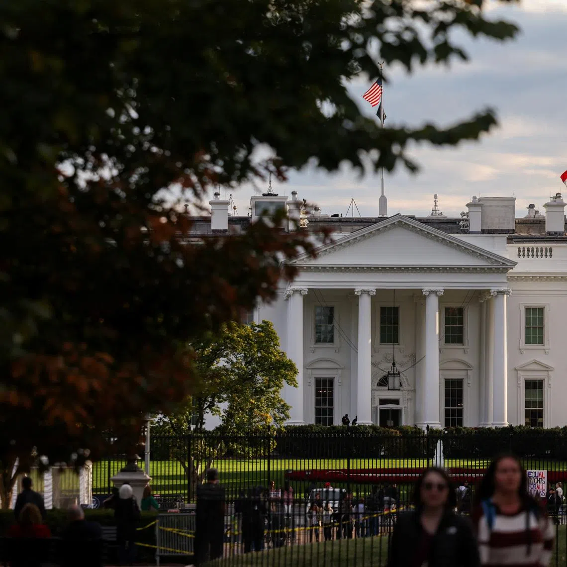 A U.S. flag flies in front of the White House as people walk by, weeks into the continuing U.S. government shutdown, in Washington, D.C., U.S., October 24, 2025. REUTERS/Kylie Cooper