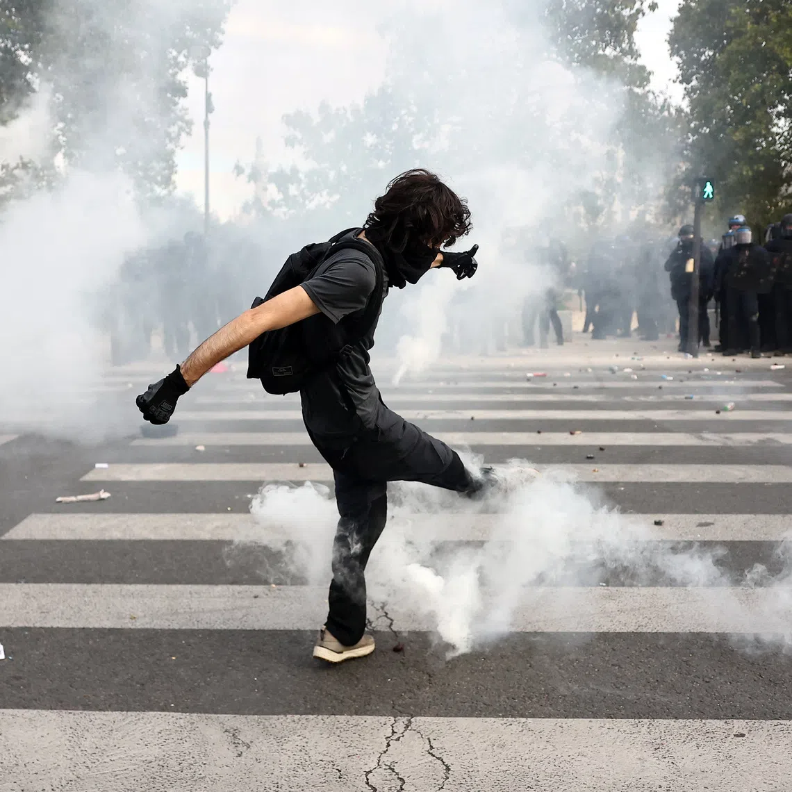 A masked student kicking a tear gas canister in France on Oct 6, as nationwide protests over decrepit conditions in French high schools descended into sporadic violence.