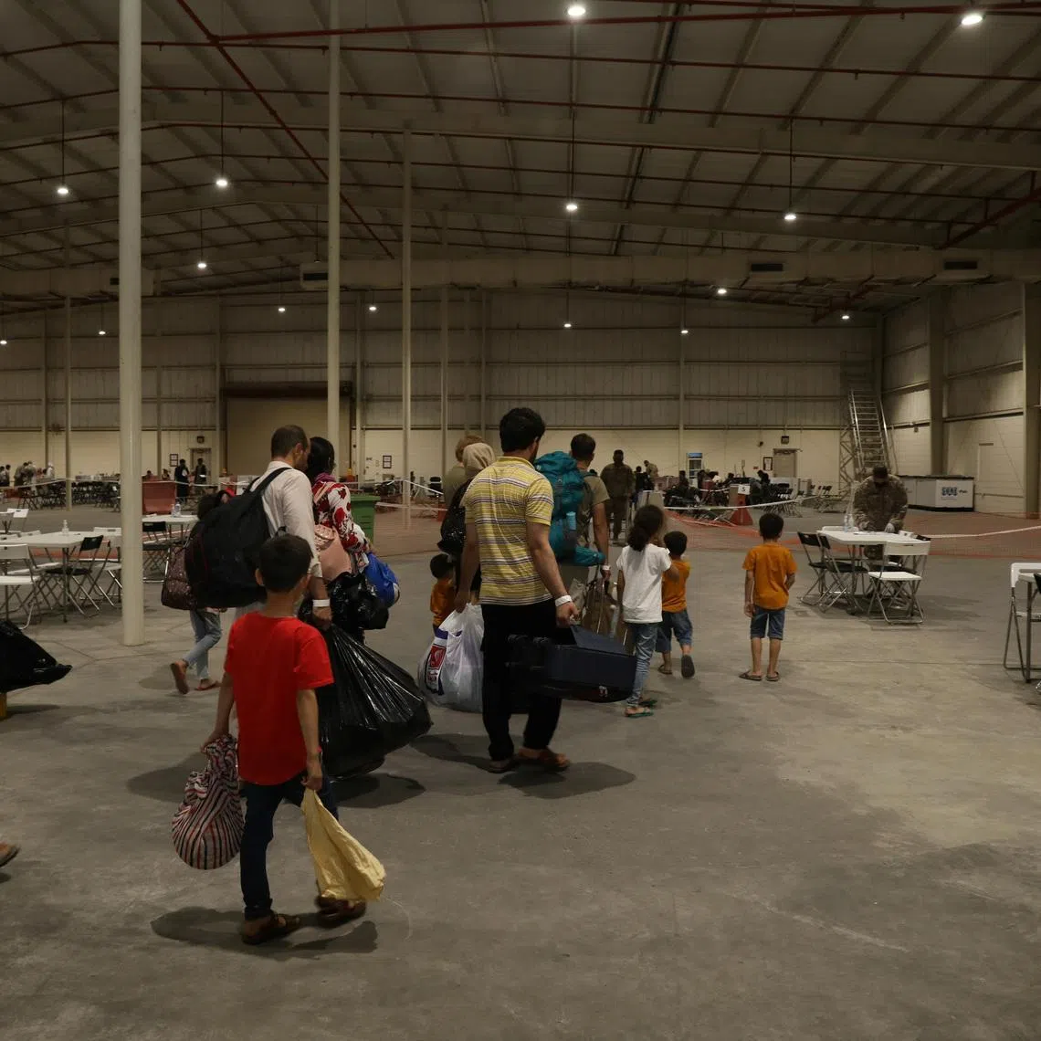 Special Immigrants from Afghanistan walk through the in-processing building after their evacuation at Camp As Sayliyah, Qatar, August 20, 2021. Picture taken August 20, 2021.  U.S. Army/Sgt. Jimmie Baker/Handout via REUTERS