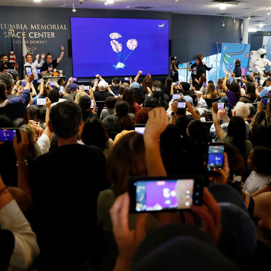 People celebrate as they watch a live broadcast of the Artemis II splashdown during a watch party at the Columbia Memorial Space Center in Downey, California.