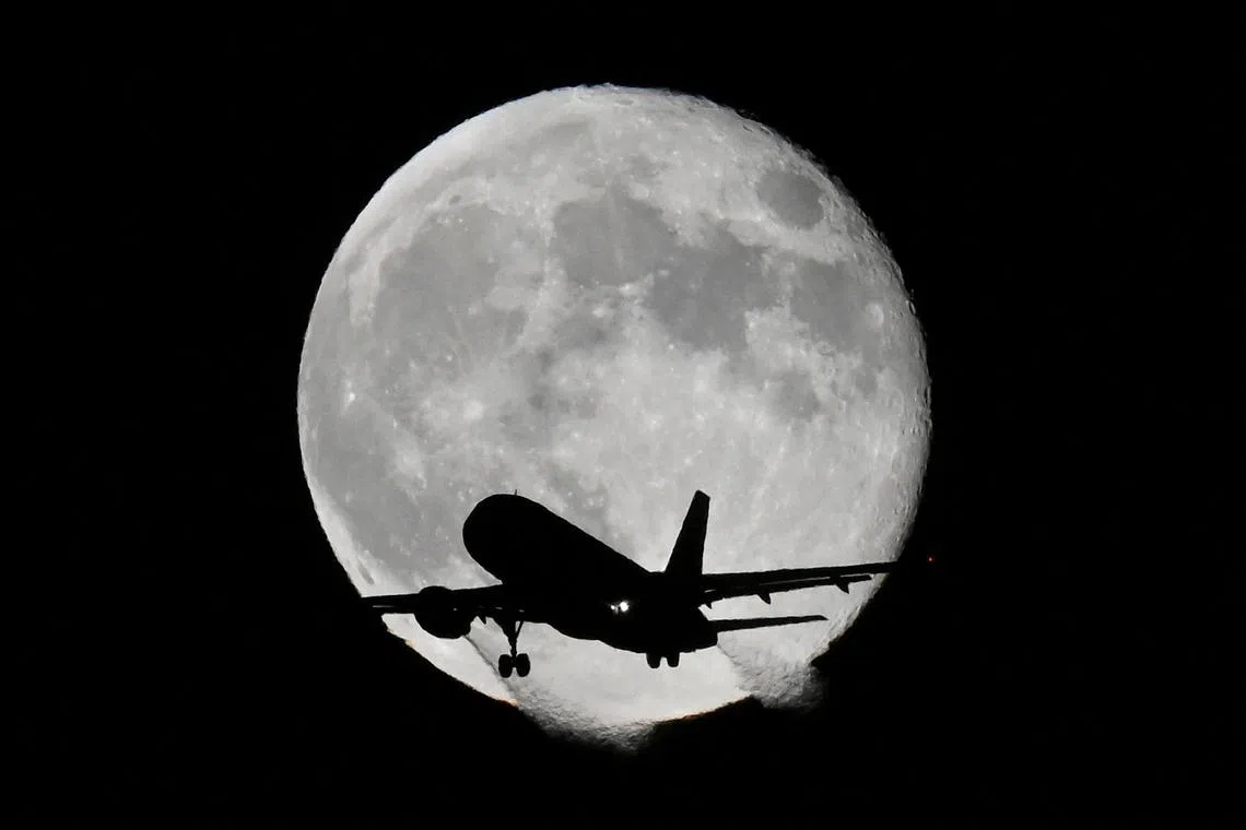 An aircraft passes in front of the moon as it makes its landing approach to Heathrow Airport in London, Britain, November 9, 2022. 