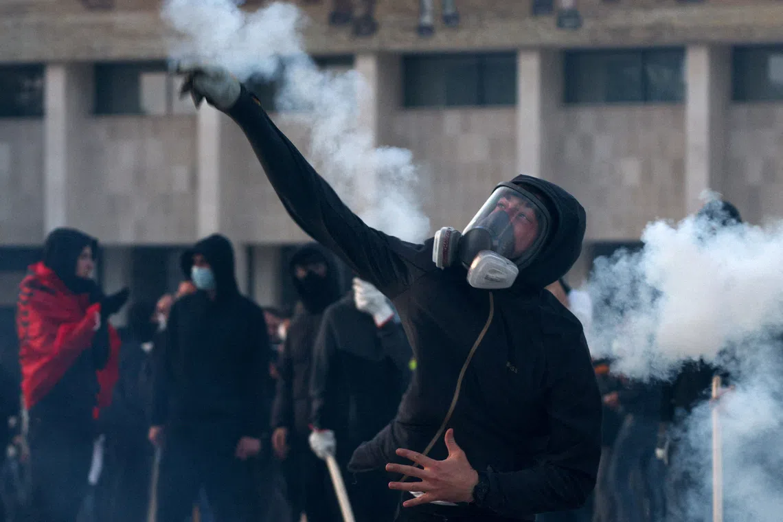 A demonstrator wearing a gas mask throws an object during an anti-government protest by students in Tirana, Albania, October 24, 2026. REUTERS/Florion Goga