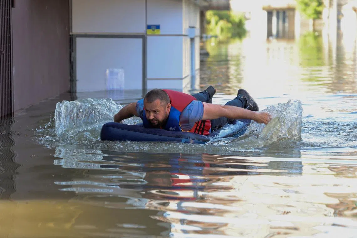 A local resident is seen on an inflatable mattress in a flooded area in Kherson on June 7, 2023, following the destruction of the Nova Kakhovka hydroelectric power plant dam. 