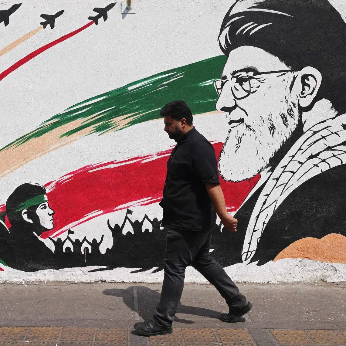 A man walking past a street mural of slain Iranian supreme leader Ayatollah Ali Khamenei, in downtown of Tehran on Aug 31.