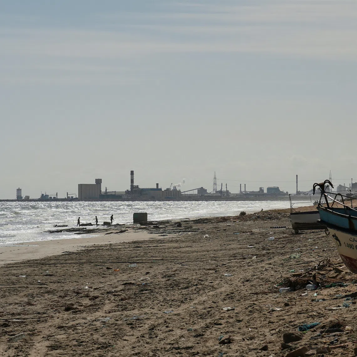 Children play on the beach with the Tunisian Chemical Group’s (CGT) phosphate complex visible in the background, in Gabes, Tunisia, October 16, 2025. REUTERS/Jihed Abidellaoui