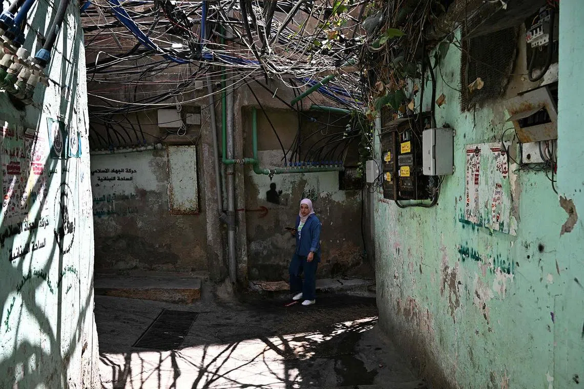 A young woman walking in a narrow alleyway at the Burj al Barajneh camp for Palestinian refugees in Beirut's southern suburbs on May 20, 2025. 