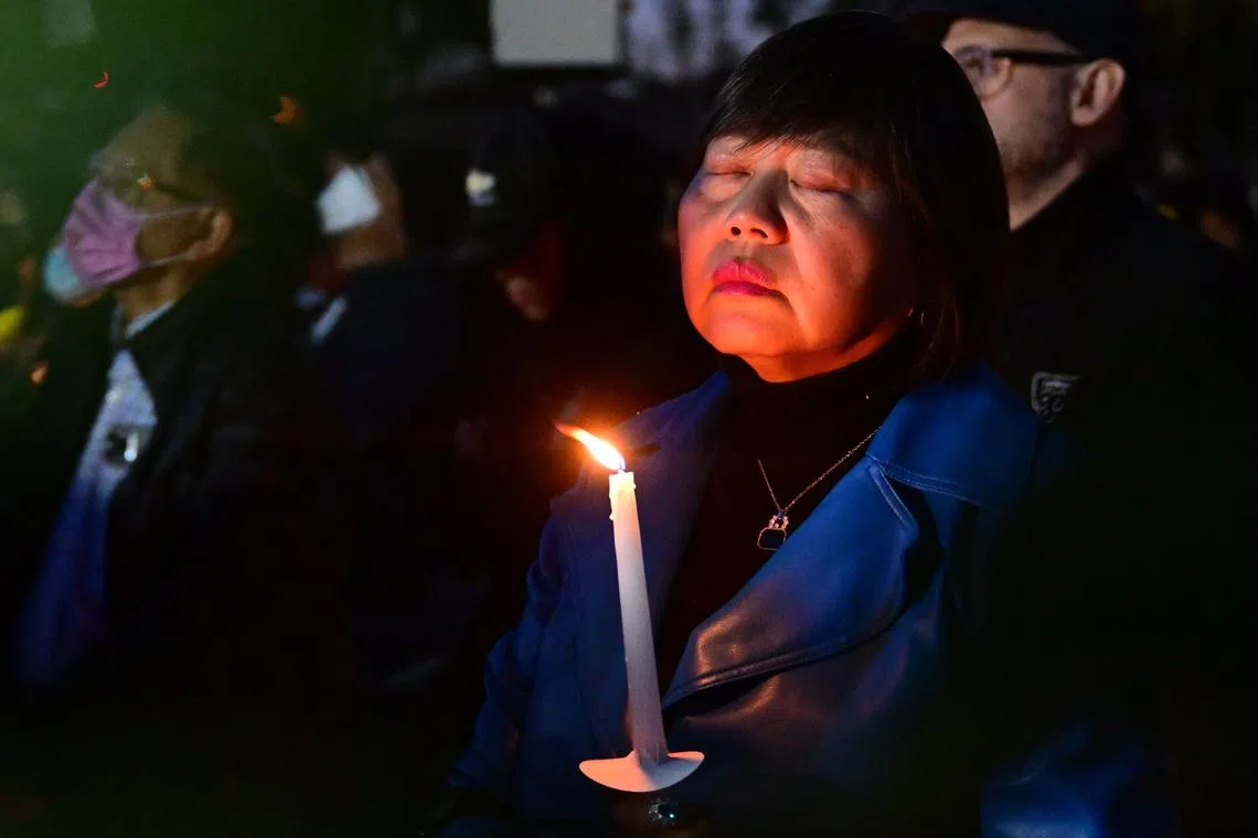 A woman closes her eyes as she pays tribute to the victims of the mass shooting at a candlelight vigil in front of City Hall in Monterey Park, California, U.S. on Jan. 24, 2023. 
