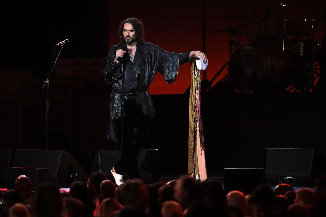 (FILES) Host British actor Russell Brand speaks onstage during the 2020 MusiCares Person Of The Year gala honoring US rock band Aerosmith at the Los Angeles Convention Center in Los Angeles on January 24, 2020. British comedian and actor Russell Brand has been accused of rape, sexual assaults and emotional abuse during a seven-year period, according to the results of a media investigation published on September 16, 2023. (Photo by MARK RALSTON / AFP)