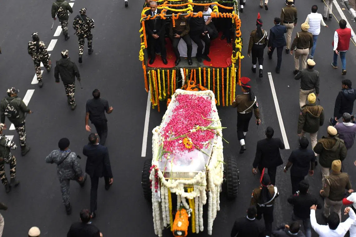 Security officials and others walk with the hearse carrying the coffin with the mortal remains of India's former Prime Minister Manmohan Singh during his funeral procession in New Delhi, India, December 28, 2024. REUTERS/Stringer