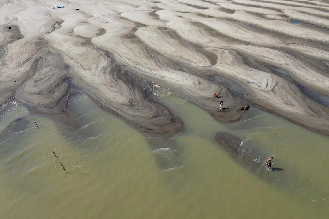 People walking on the sand on the shore of the Solimoes River, in the Manacapuru region, Amazonas, Brazil, Oct 3, 2024. 