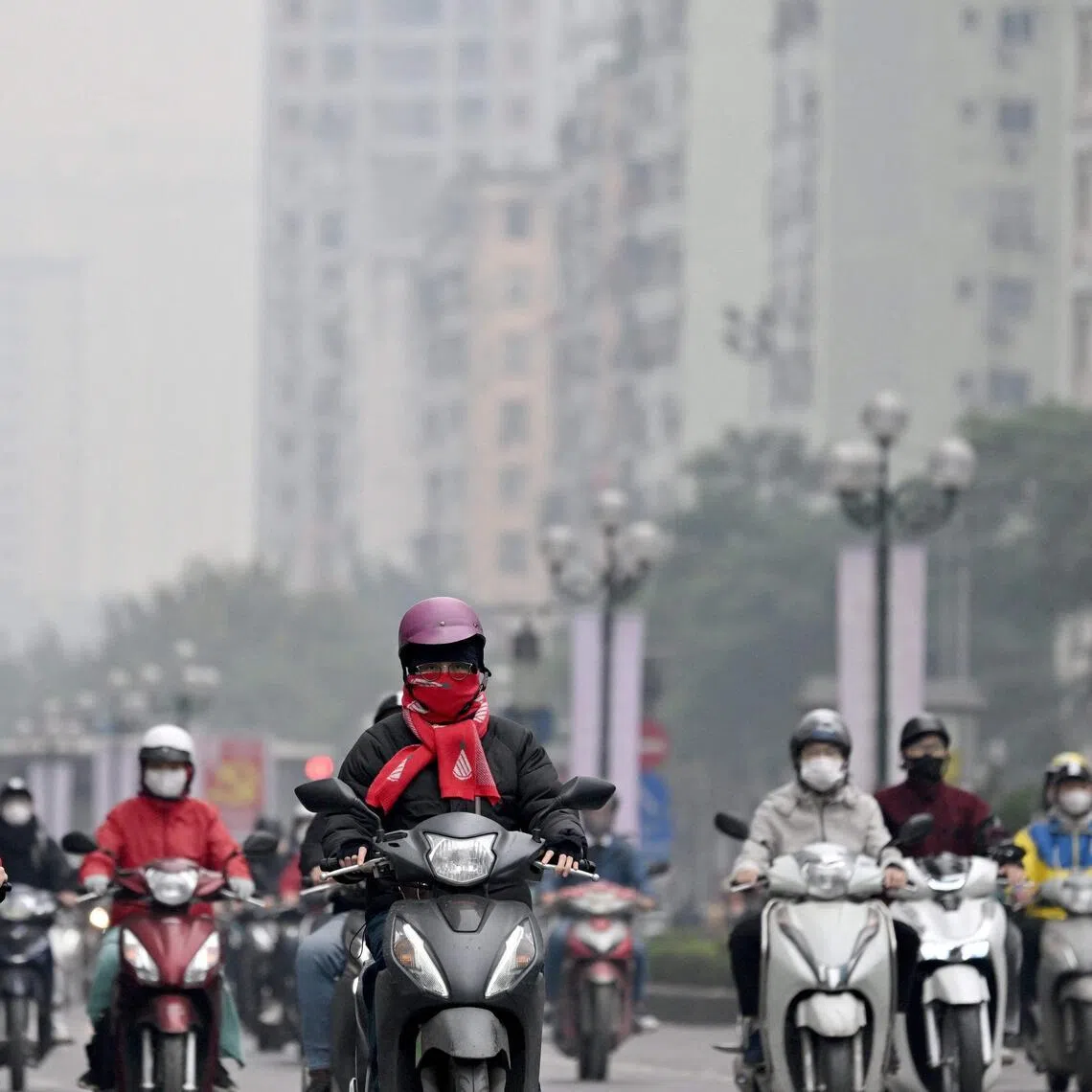 Motorists make their way on a street amid heavy air pollution conditions in Hanoi on January 15, 2026. (Photo by Nhac NGUYEN / AFP)
