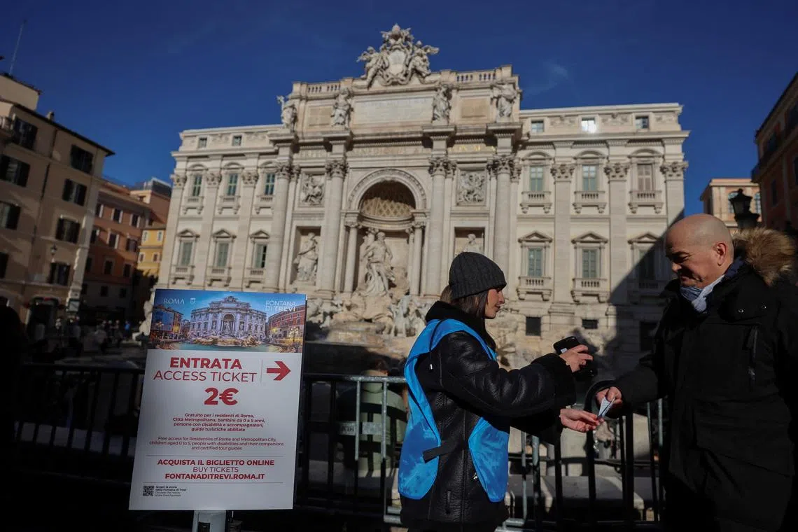 A tourist shows his two-euro ticket to access the viewing area of the Trevi Fountain in Rome, after the city introduces paid entry at several monuments and museums previously free, in Rome, Italy, February 2, 2026. REUTERS/Vincenzo Livieri