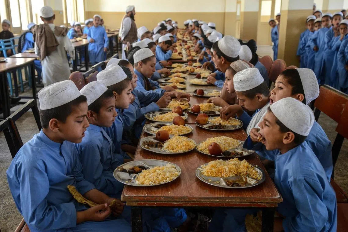 TOPSHOT - Afghan orphan boys eat their lunch at the Mohammadi Orphanage in Kandahar on May 3, 2026. (Photo by Sanaullah SEIAM / AFP)