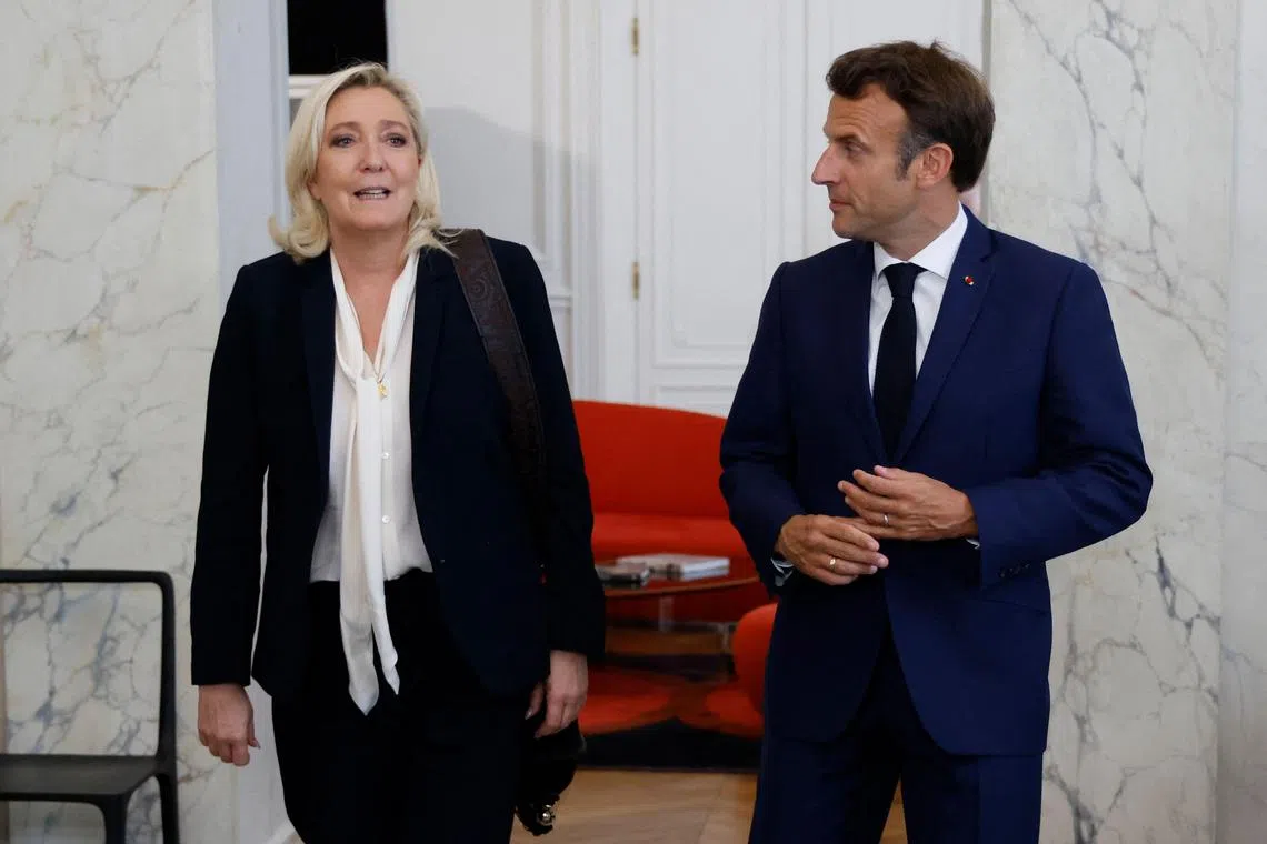 (FILES) French far-right Rassemblement National (RN) leader and Member of Parliament Marine Le Pen (L) is escorted by France's President Emmanuel Macron after talks at the presidential Elysee Palace, in Paris, on June 21, 2022, two days after France's legislative elections. Marine Le Pen denounced the "cynicism" of a "president in a state of siege, whistled at the Agriculture Fair, and who believes he can find political solution in warlike postures which have stunned the French", regarding Macron's recent remarks on the possible sending troops to Ukraine. (Photo by Ludovic MARIN / POOL / AFP)