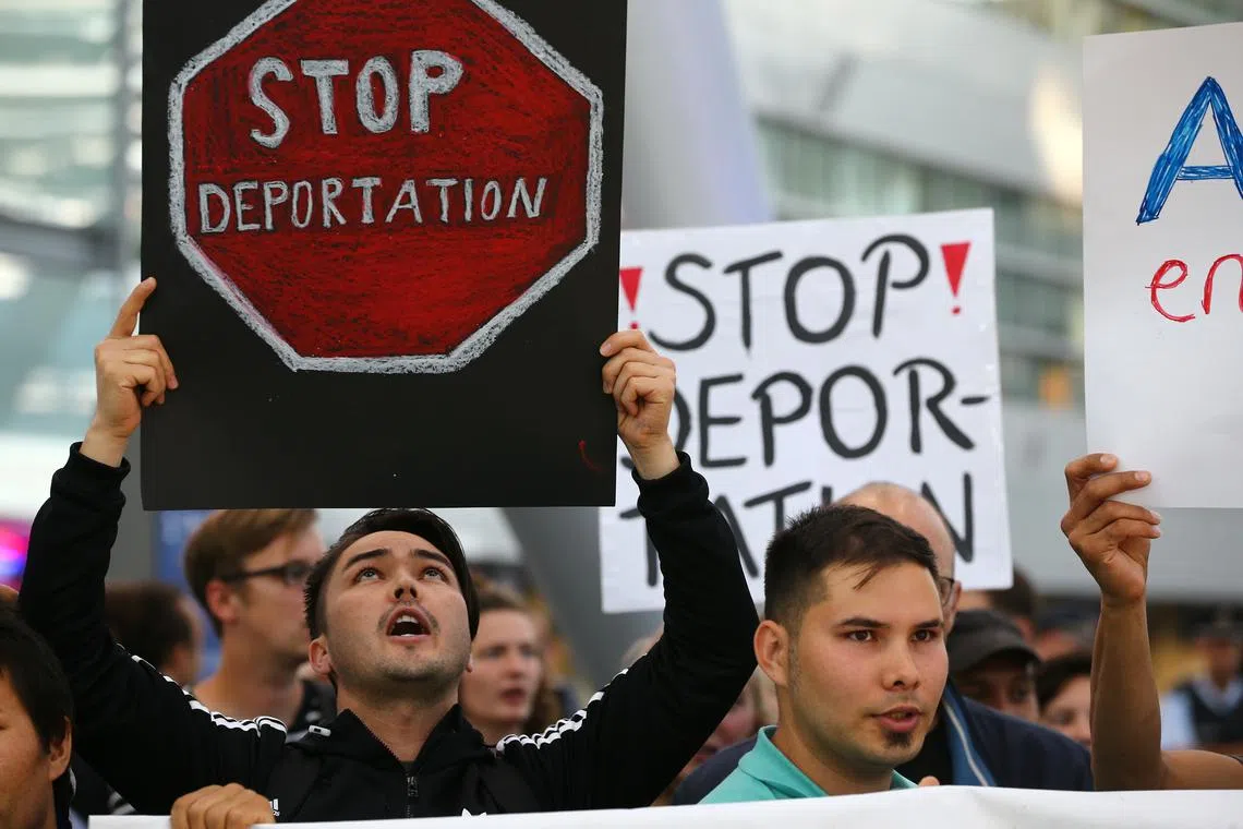 FILE PHOTO: People hold signs as they protest against the German government's decision to deport migrants who were denied asylum, at Duesseldorf Airport, Germany September 12, 2017. REUTERS/Wolfgang Rattay/File Photo
