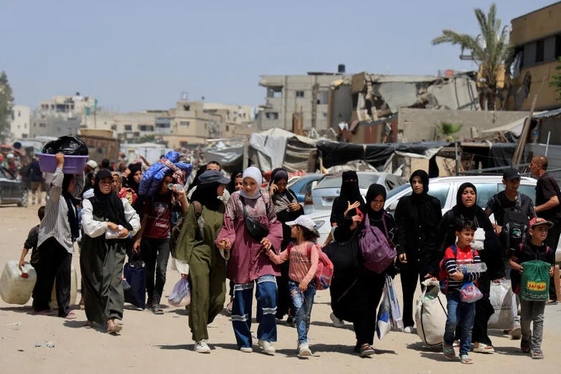 Palestinians make their way with belongings as they evacuate from eastern Khan Younis, in the southern Gaza Strip, on May 19.