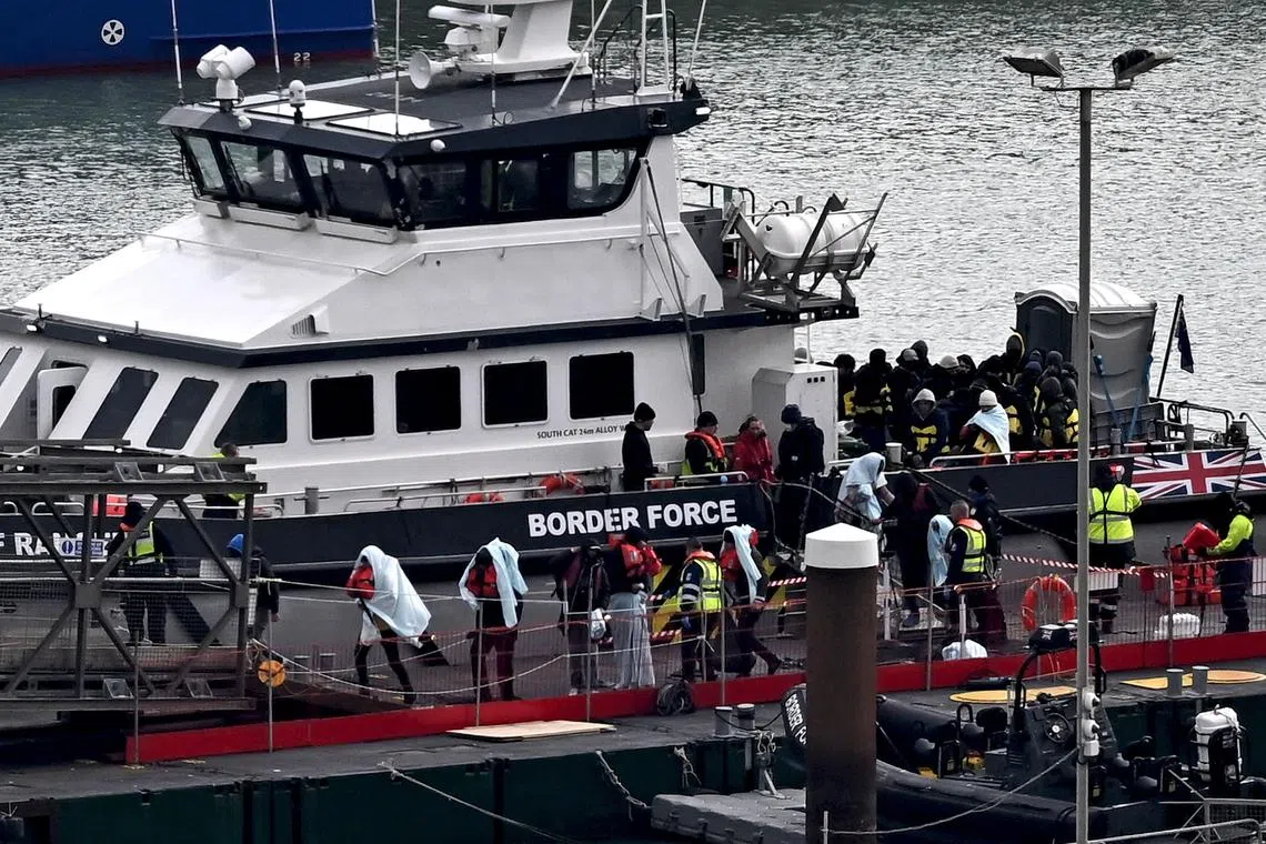 Migrants are escorted ashore from a UK Border Force vessel in Dover, south-east England, on March 6, 2023.