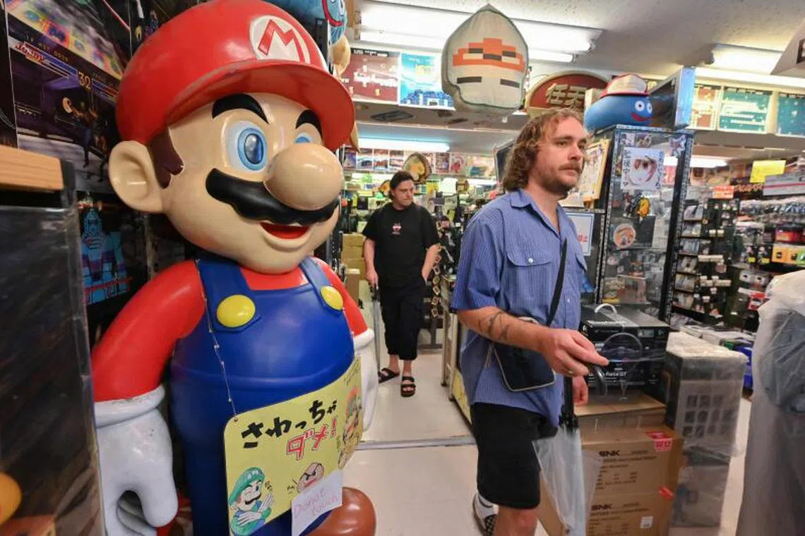 Visitors walking past a Super Mario statue while shopping at Super Potato, a shop selling vintage video games and memorabilia in the popular electronics shopping area of Akihabara in central Tokyo on June 18, 2024.