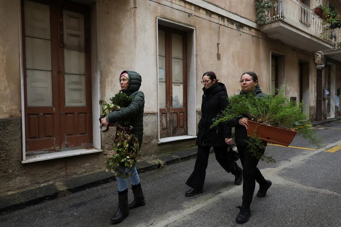 Benedetta Ragusa (L) and her friends remove flowerpots from her pizzeria as residents scramble to remove belongings and mementos from homes in high-risk areas following a landslide in Niscemi, Sicily, Italy, January 31, 2026. REUTERS/Fatos Bytyci