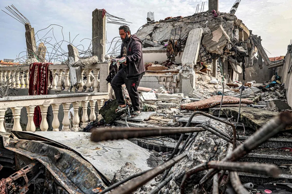 A man salvages a copy of the Quran from the rubble of a building hit by Israeli bombardment in southern Gaza on March 26.