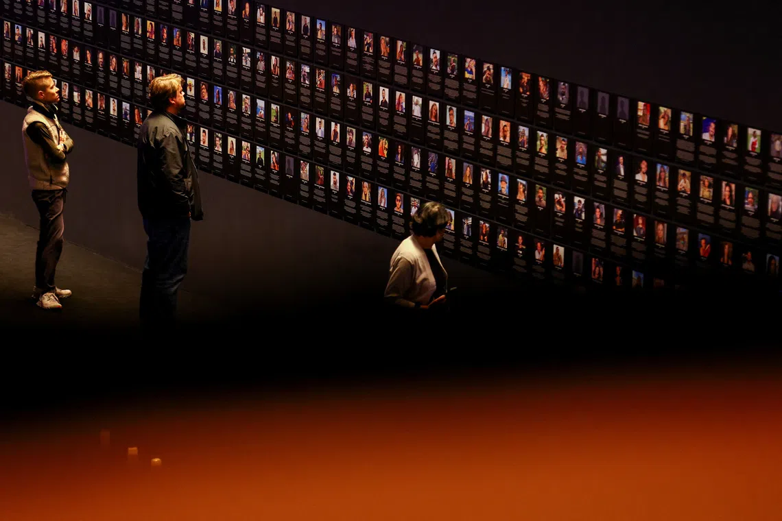 People looking at the pictures of victims of Hamas' Oct 7, 2023 attack on Israel, during the public opening and European debut of commemorative installation "The Nova Music Festival Exhibition", at the historic Tempelhof Airport in Berlin, Germany, Oct 7, 2025.