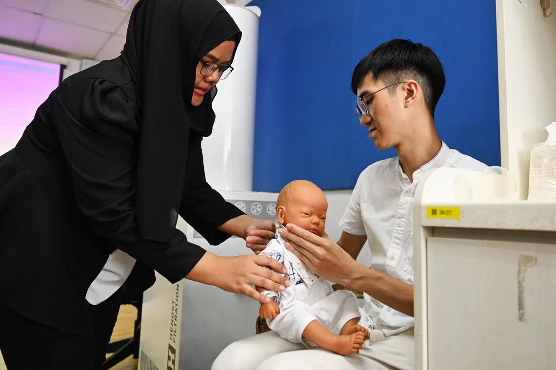 Nur Azlina Subari, Lead Lecturer at NIEC, teaches Mr Justin Heng, trainee teacher, how to attend to a baby during a lesson on Oct 17.