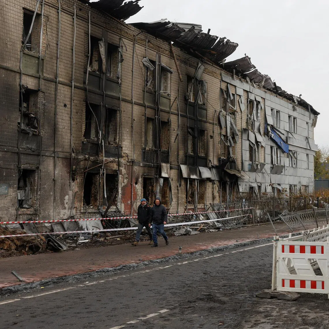 Residents walk past a dealership building in Kyiv hit by a Russian missile strike on Oct 27.